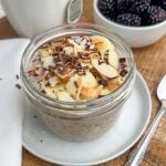 blended banana chia pudding in a mason jar topped with banana, almonds, and shaved chocolate.