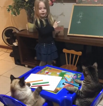 Little_girl_teaching_her_cats.png