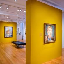 Exhibition space with yellow panels displaying portraits.