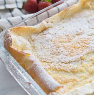 German Pancakes just out of the oven, dusted with powdered sugar in a glass baking dish.