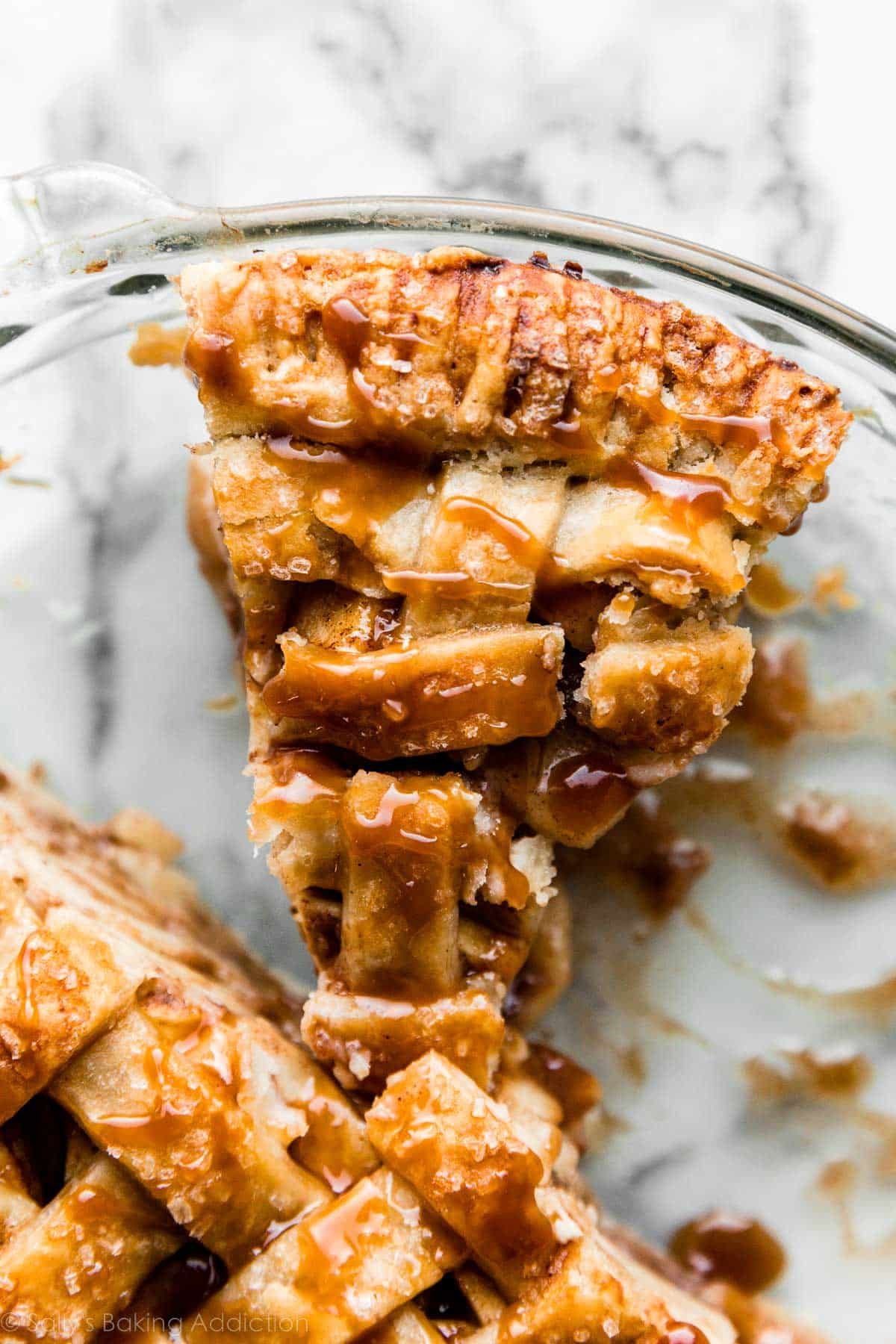 slice of salted caramel apple pie in a glass pie dish.