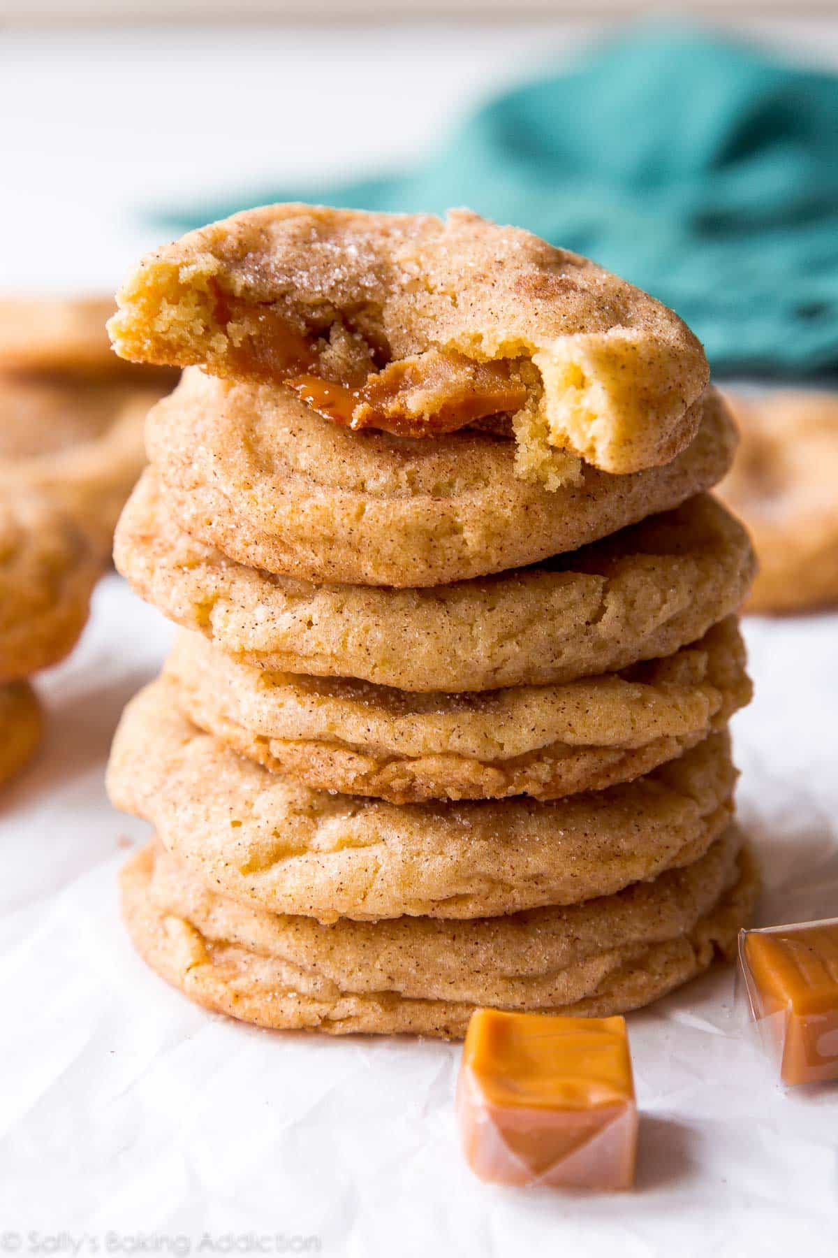 stack of caramel snickerdoodle cookies with one broken in half showing the caramel inside