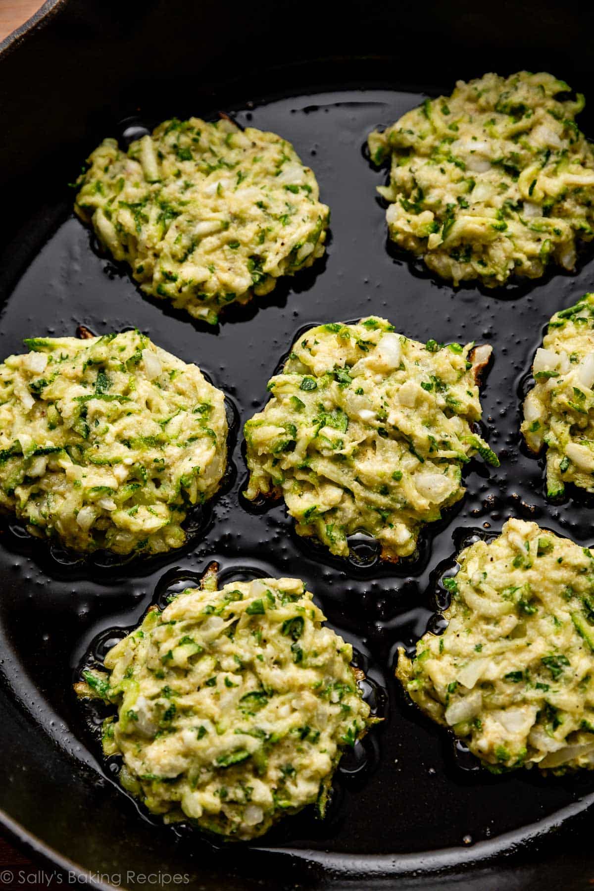 cooking zucchini cakes in cast iron skillet.