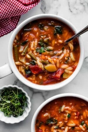 overhead photo of bowls of tomato and broth-based minestrone soup with orzo pasta.