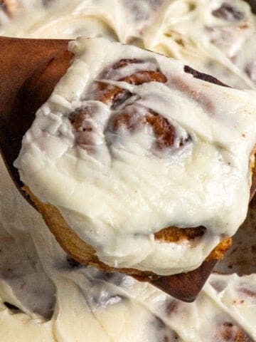 A wooden spoon holding a crock pot cinnamon roll.