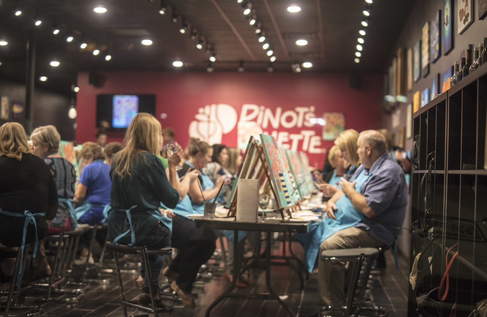 large group of adults painting inside Pinot's Palette