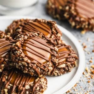 A plate of chocolate Turtle Cookies filled with caramel and drizzled with chocolate.