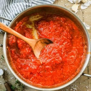 A classic Marinara Sauce recipe in a pan with a wooden spoon.