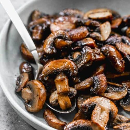 A plate of sauteed mushrooms with a spoon.