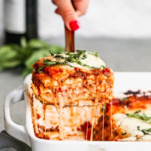 An easy Lasagna recipe with a square being lifted from the pan to show the cheesy layers.