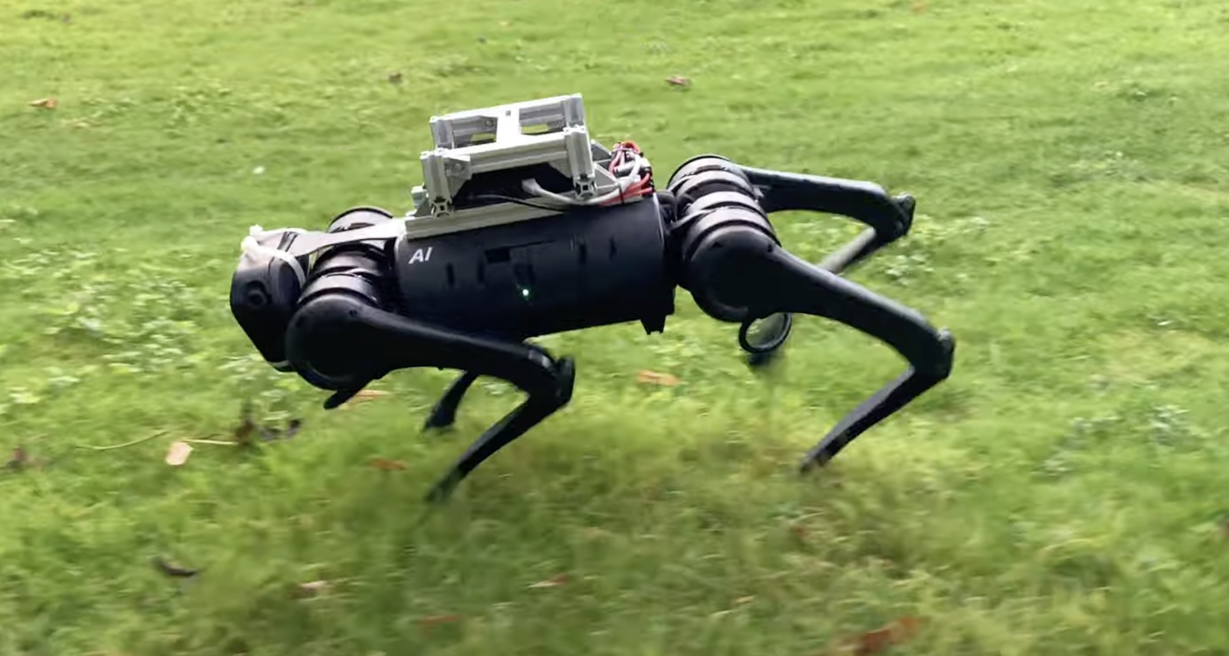 black four-legged robot running in a green feild