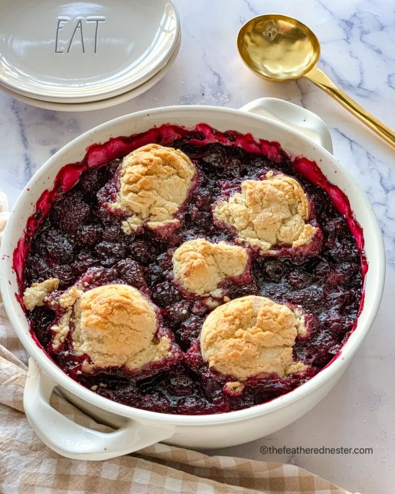 a white casserole dish of blackberry cobbler ready to serve.