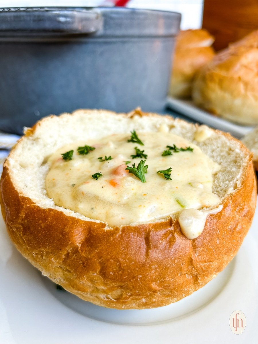 White chowder in a sourdough bowl on a white plate.