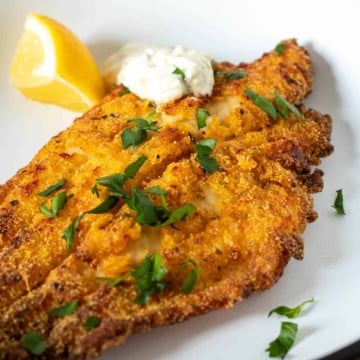 Golden brown air fryer southern catfish withhomemade tartar sauce and lemon.