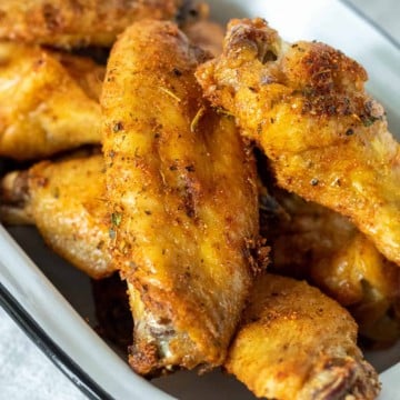 Air fryer chicken wings piled in a pan.