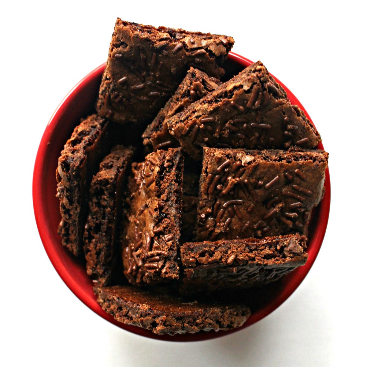 Squares of brownie brittle in a red bowl.