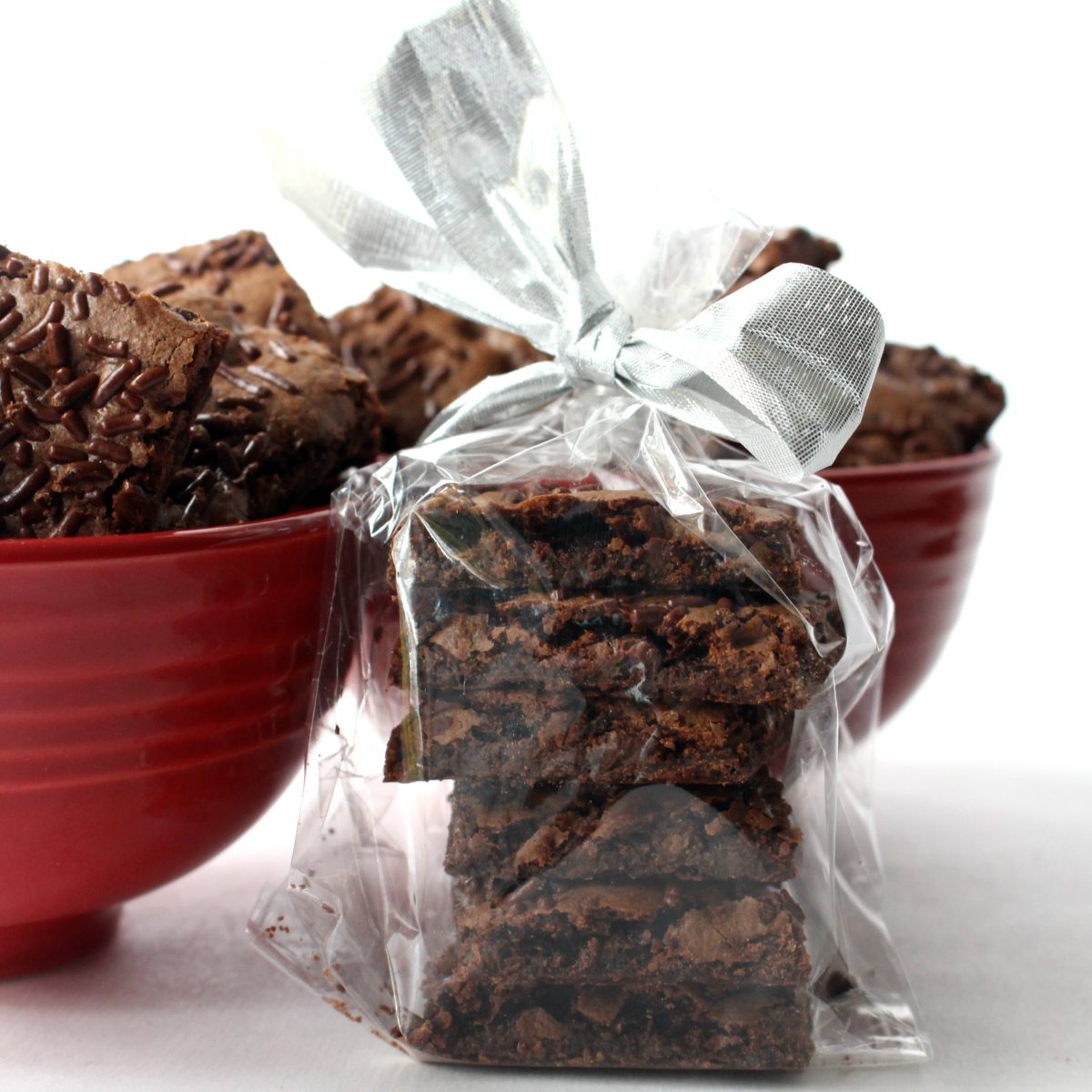 Wrapped stack of Malted Milk Brownie Bark with two red bowls in the background..