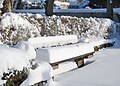 Eine verschneite Parkbank beim Friedhof