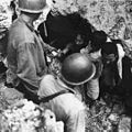 Marines assist Japanese emerging from cave fortifications in the cliffs of Tinian. Surrender was unusual -- most Japanese fought to their death or committed suicide. July 1944.