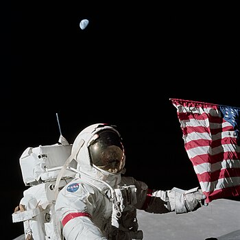 Eugene Cernan with the American flag and the earth in the moon's sky.