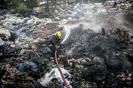 A brazilian fireman fighting a fire on a garbage dump