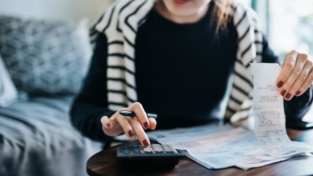 Article thumbnail: Cropped shot of young Asian woman managing personal banking and finance at home. Planning budget and calculating expenses with calculator. Managing taxes and financial bills. Wealth management. Home budgeting