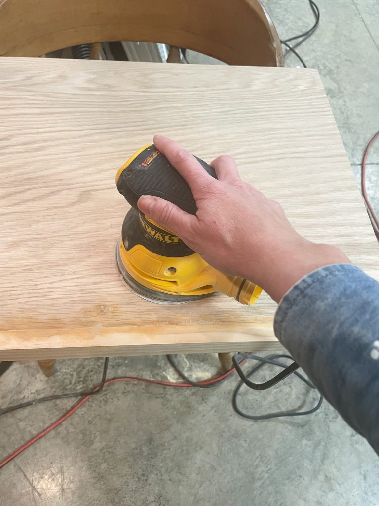 sanding the wood shelf with orbital sander