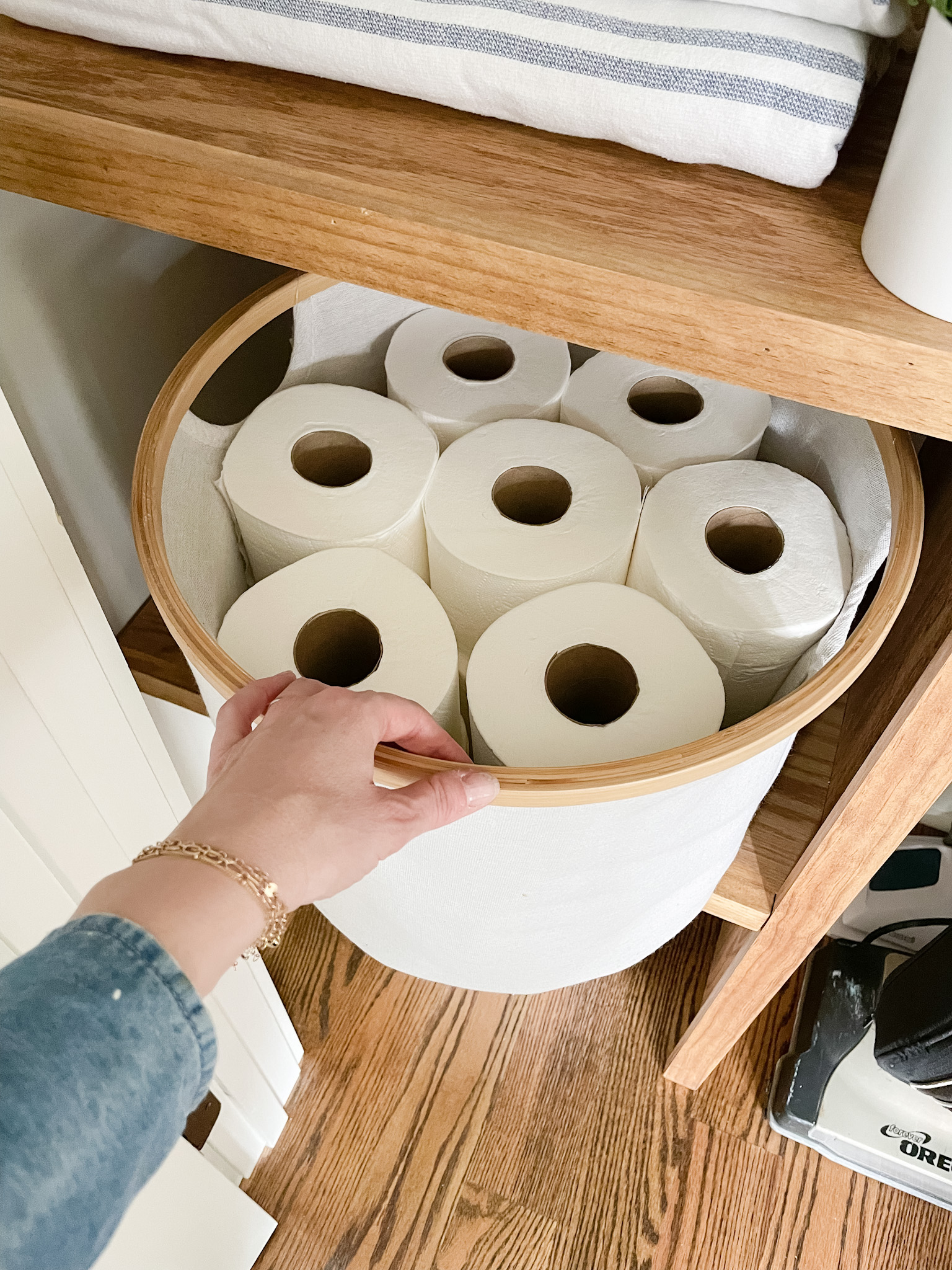 hand pulling out bin of toilet paper from the shelf