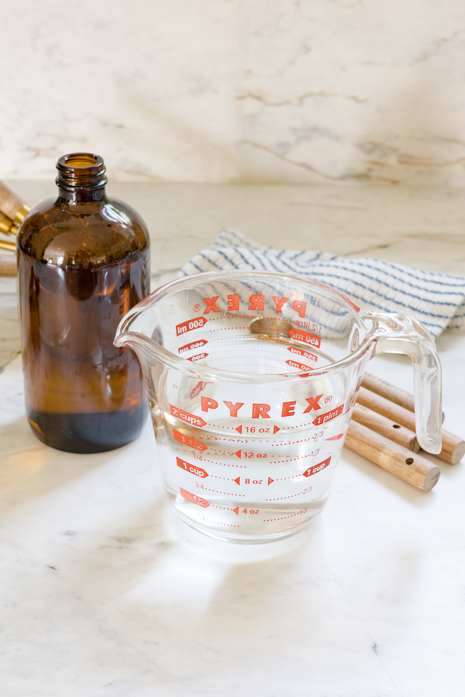 glass amber bottle with glass measuring cup with water