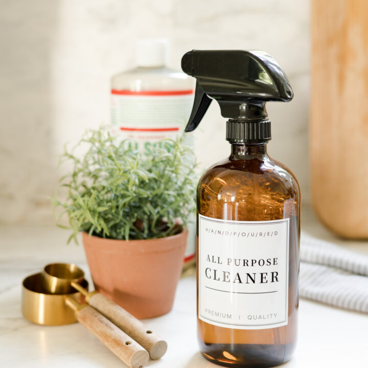 all purpose cleaner in amber glass bottle sitting on countertop next to green plant