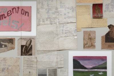 A grouping of papers with scrawls on them posted to a wall.