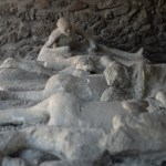 A group of casts of people lying around in a brick room.