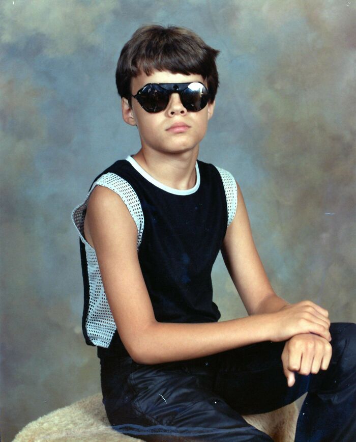 Young kid in sunglasses and a sleeveless top posing, reflecting on blunder years.