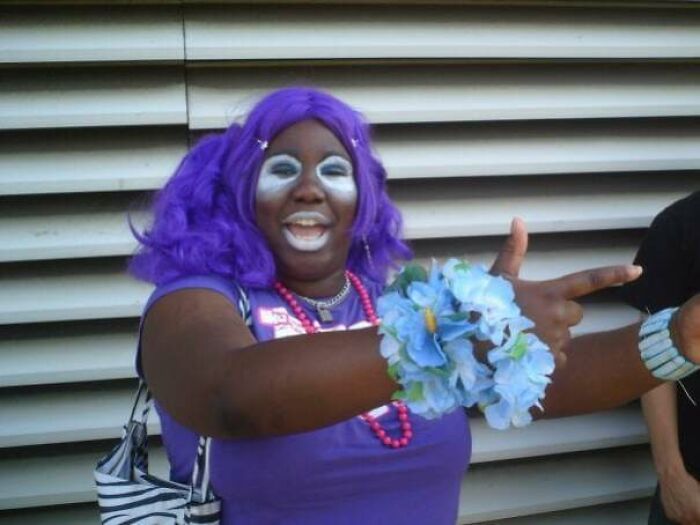 Person in purple outfit and wig posing playfully, representing blunder years.