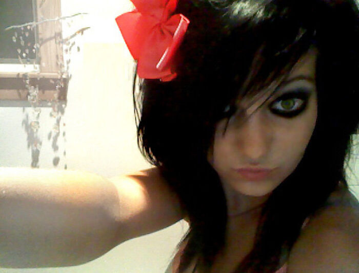 Young woman during her blunder years, with heavy eye makeup and a red bow in her dark hair.