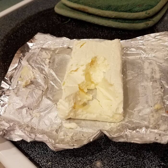 Unwrapped cream cheese with a large uneven bite taken out, possibly by boyfriends or husbands.