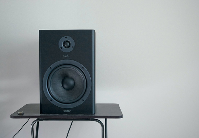 Black speaker on a small table, emphasizing noise in a calm, minimalist setting.