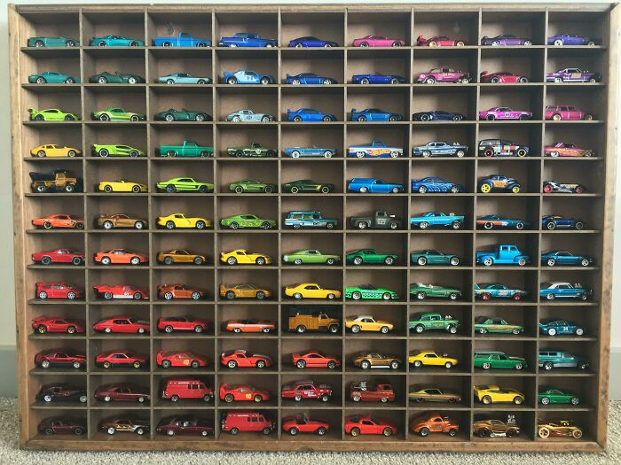 Collection of colorful miniature cars neatly displayed in a wooden case.