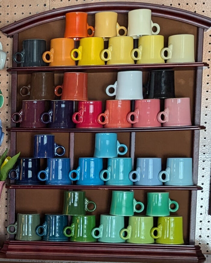 Colorful mugs on wooden shelves displaying unexpected unique collections.