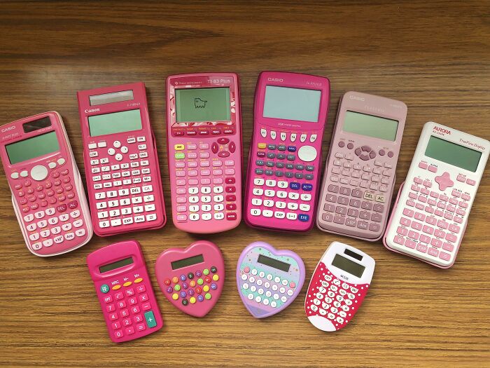 Collection of pink calculators displayed on a wooden table, showcasing unexpected unique collections.