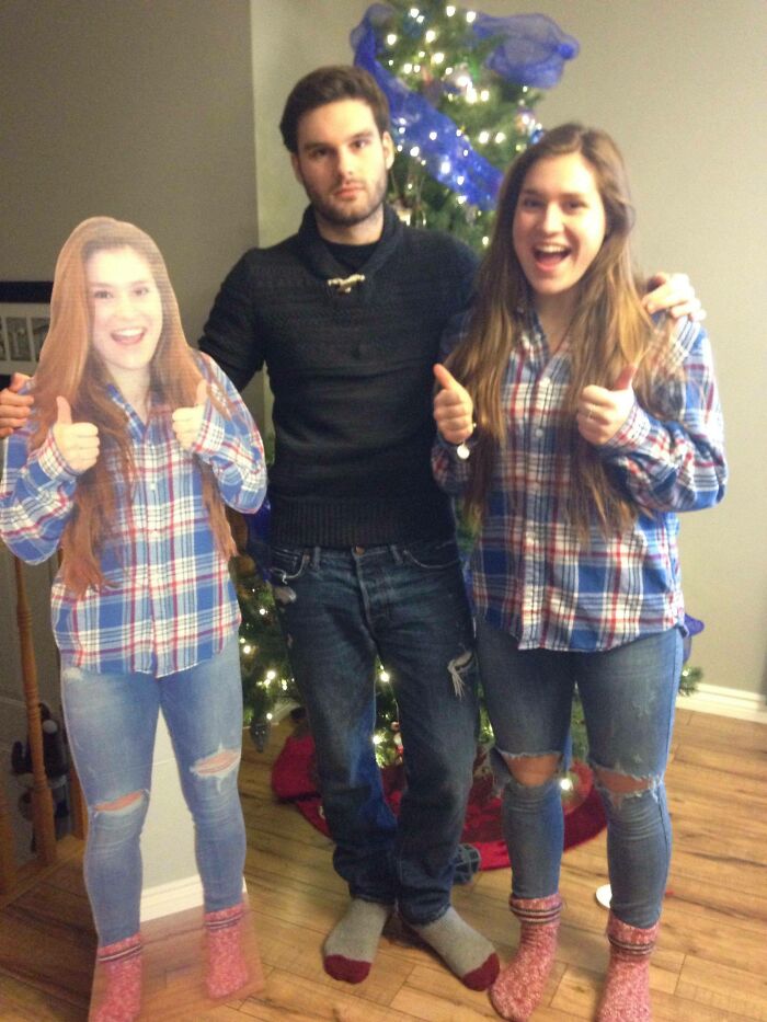 Man with a real person and cardboard cutout, both wearing matching plaid shirts, in front of a Christmas tree. Hilarious trolling gift.