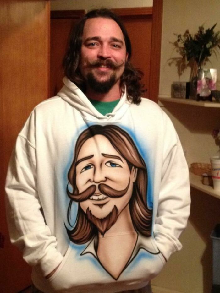 Man wearing a hoodie with a cartoon self-portrait, showcasing a hilarious Christmas gift.