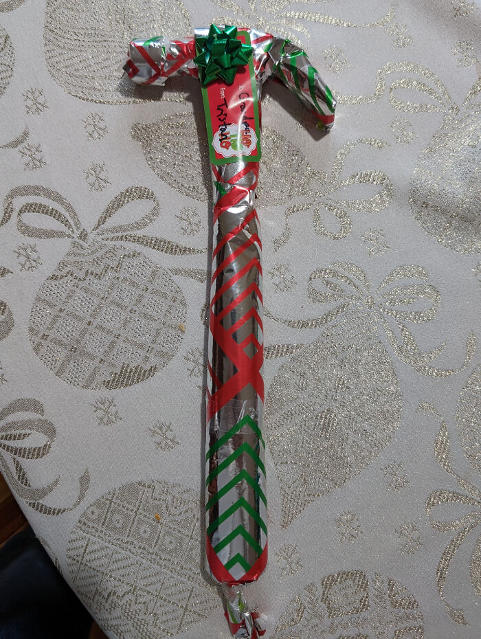 Hilarious trolling Christmas gift of a hammer humorously wrapped in festive paper with a green bow.