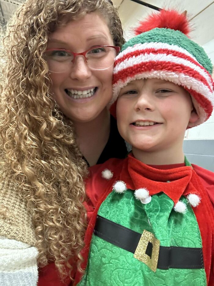 Smiling woman with glasses and child in festive costume, showcasing a wholesome Christmas moment.