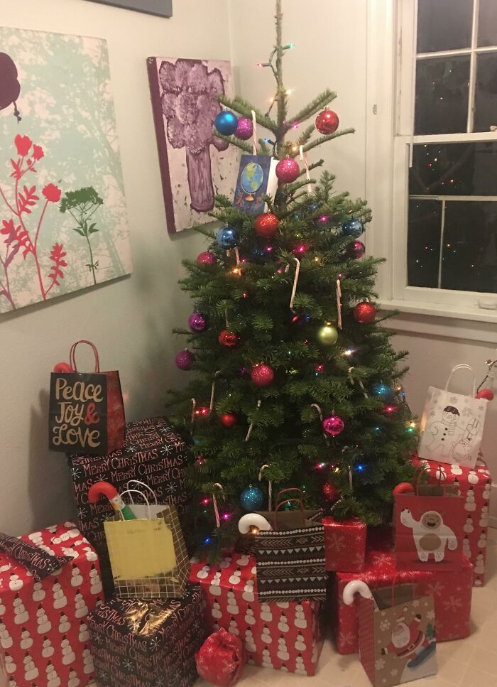 Small Christmas tree with colorful ornaments and surrounded by gifts, creating a wholesome festive atmosphere.