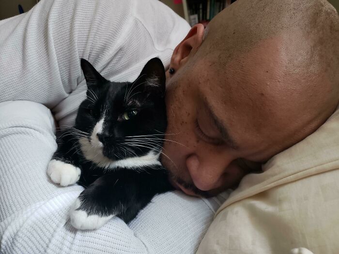 Man cuddling with a black and white cat, portraying a wholesome moment.