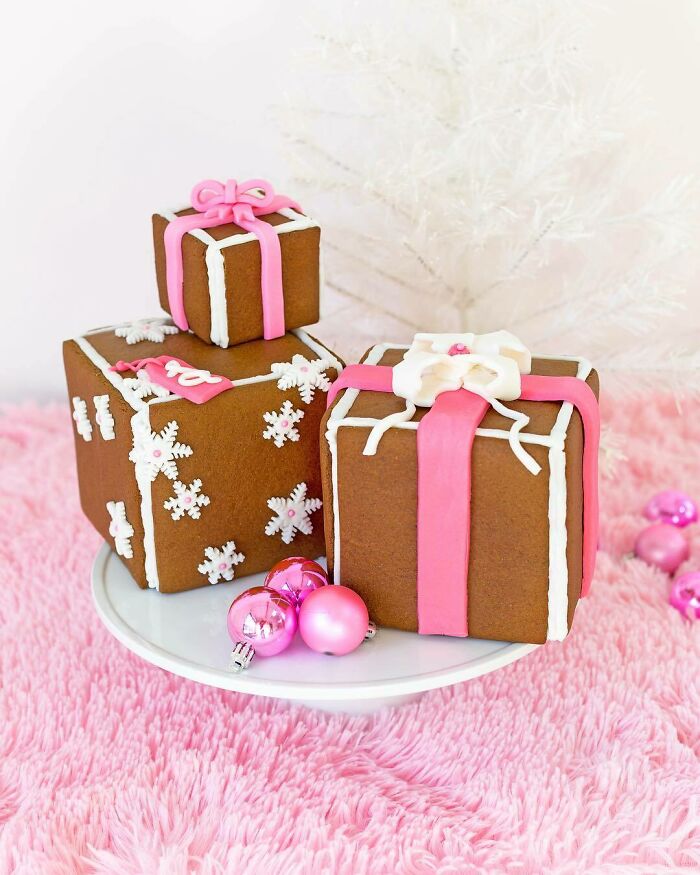 Gingerbread gift boxes with pink and white icing on a plate, surrounded by pink ornaments, perfect Christmas snack food idea.