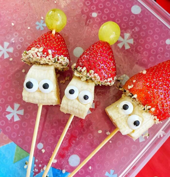 Festive Christmas snack ideas with skewered fruits, including bananas, strawberries, grapes, and edible googly eyes.