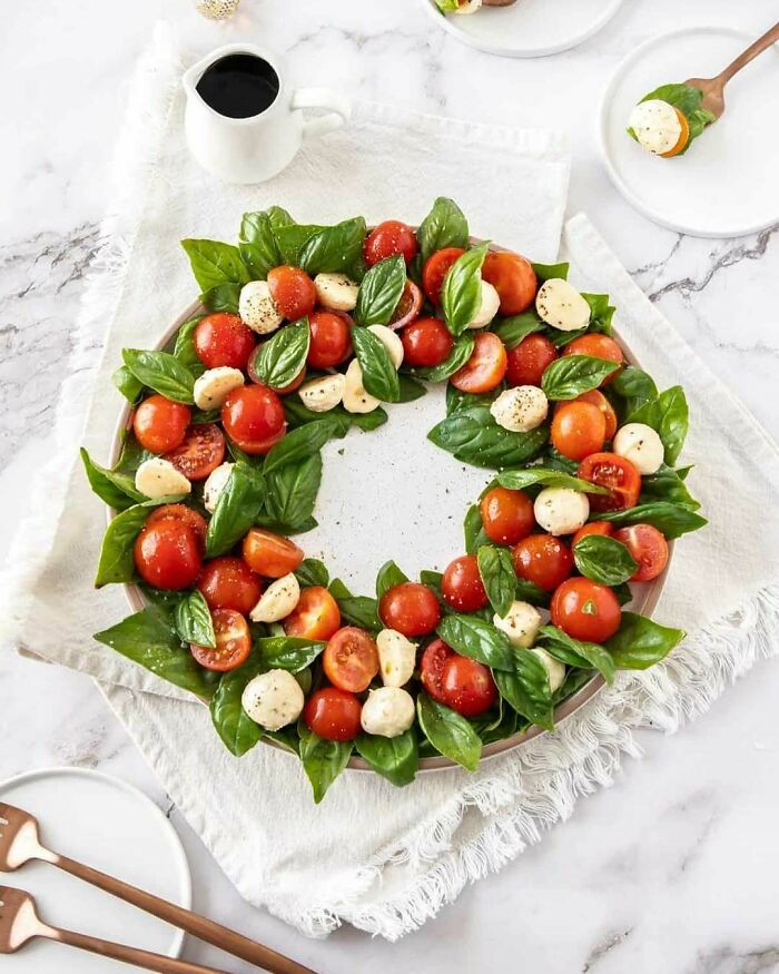 Christmas snack food idea: Caprese wreath with tomatoes, mozzarella, and basil on a white plate.