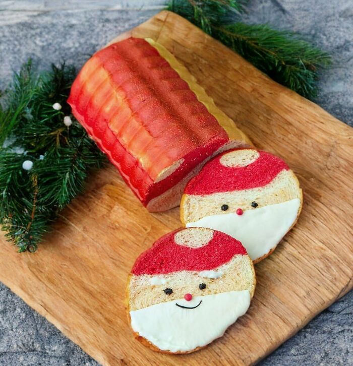 Festive Christmas snack bread shaped like Santa on a wooden board with evergreen branches.